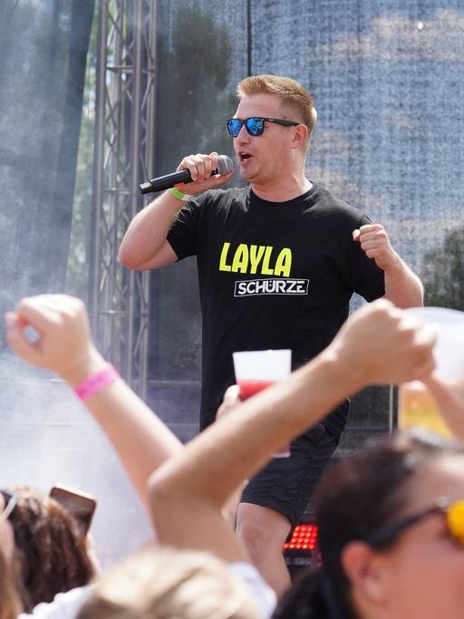 Ein Mann auf einer Bühne, davor Publikum mit Bierbechern in den Händen: Schürze mit "Layla" auf der Mallorca-Live-Party 2022  in Bad Kreuznach.