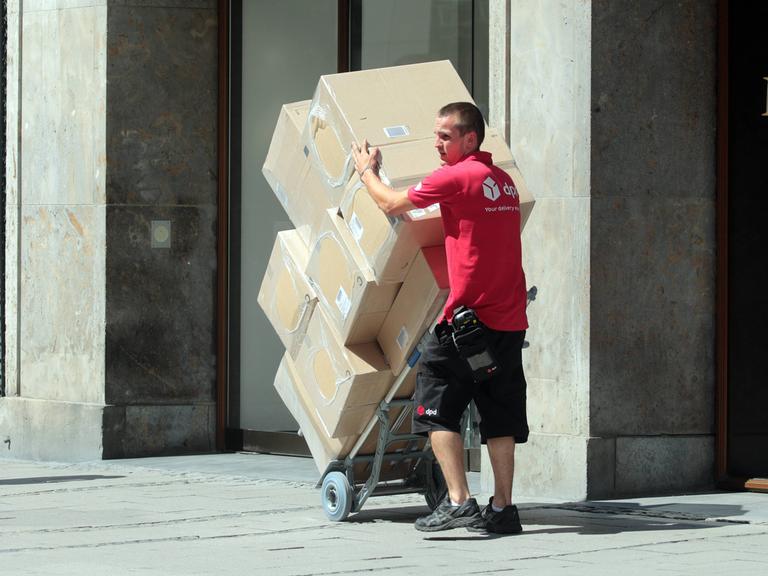 Ein Lieferant hat viele große Pakete auf einer Sackkarre gestapelt.