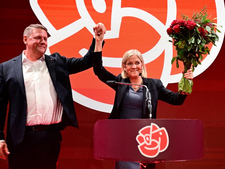 Tobias Baudin, Parteisekretär der Sozialdemokraten, und Parteivorsitzende Magdalena Andersson halten die erhobenen Hände und einen Strauß Rosen in die Höhe Tobias Baudin, Parteisekretär der Sozialdemokraten, und Parteivorsitzende Magdalena Andersson halten die erhobenen Hände und einen Strauß Rosen in die Höhe