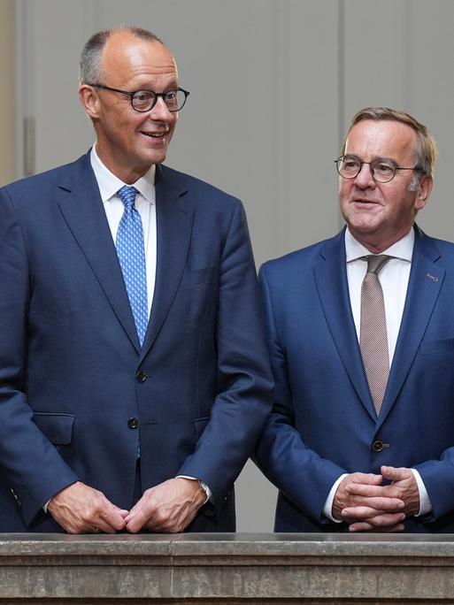 Bundeskanzler Friedrich Merz steht an einem Geländer mit Verteidigungsminister Boris Pistorius und Finanzminister Lars Klingbeil vor der Sitzung des Bundeskabinett im Bundesministerium der Verteidigung am 27.08.2025