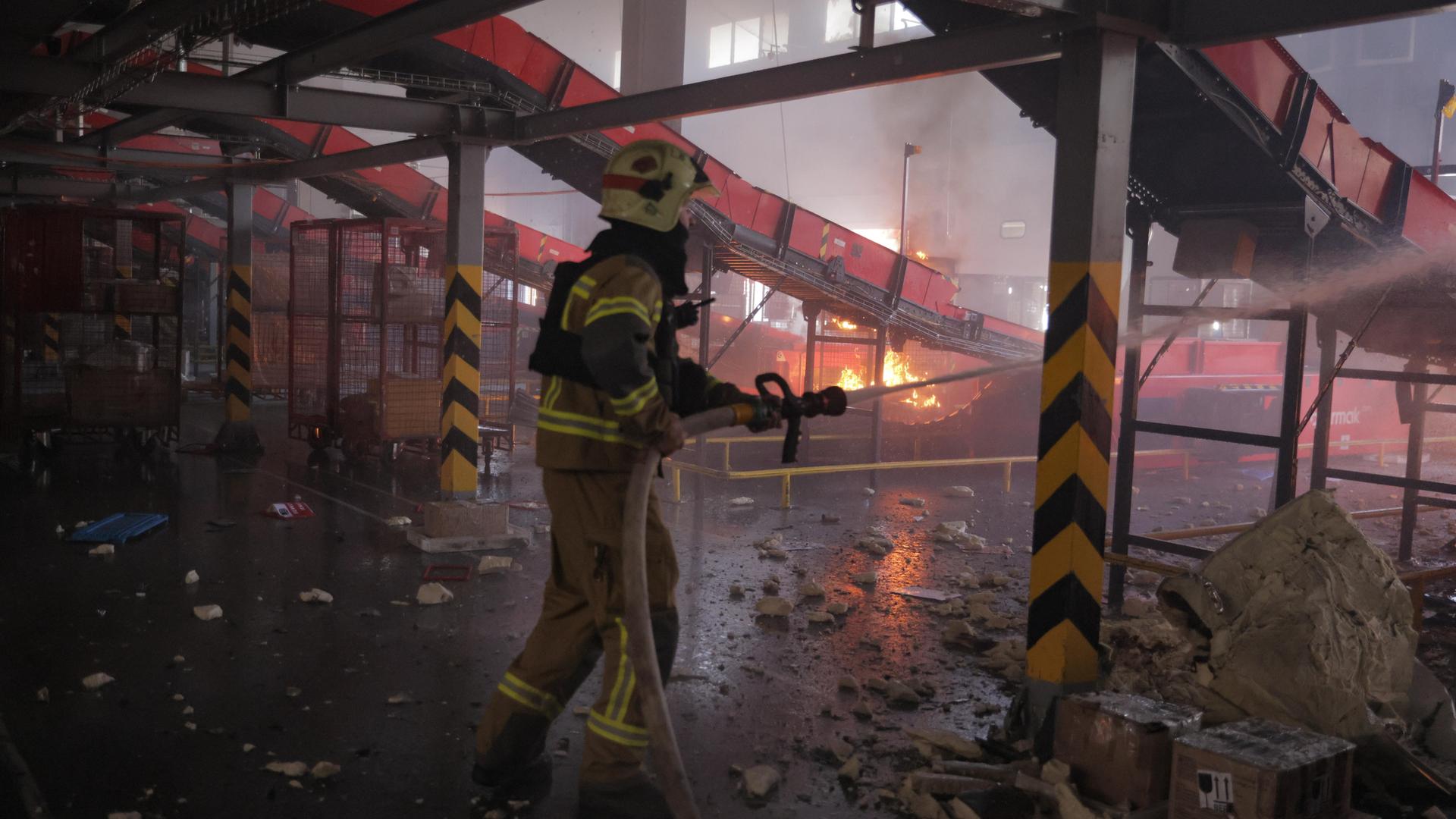 Feuerwehrleute löschen nach einem russischen Luftangriff einen Brand in einem Postlager.