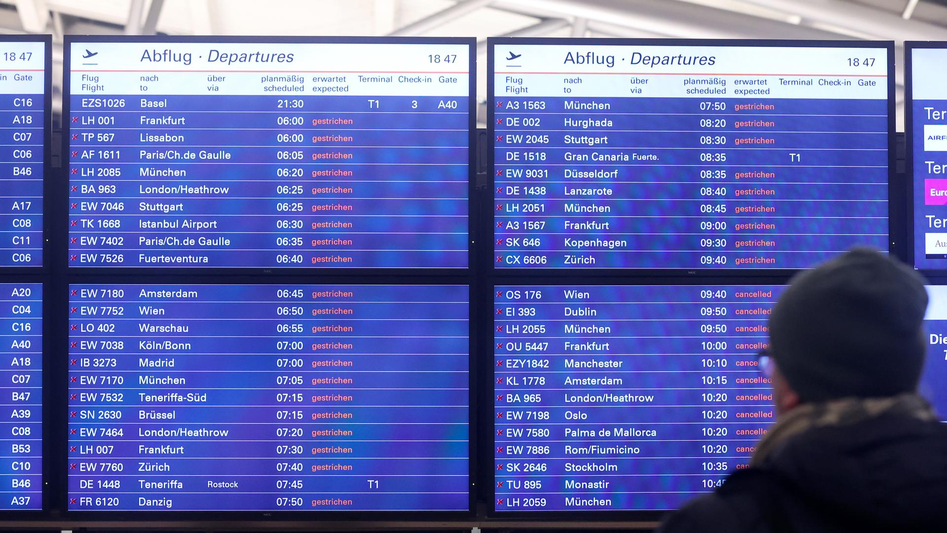 Ein Mann schaut am Flughafen Hamburg auf eine Anzeigentafel, auf der zahlreiche gestrichene Flüge angezeigt werden. Ein Mann schaut am Flughafen Hamburg auf eine Anzeigentafel, auf der zahlreiche gestrichene Flüge angezeigt werden.