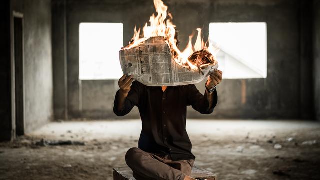 Ein Mann hält eine brennende Zeitung.