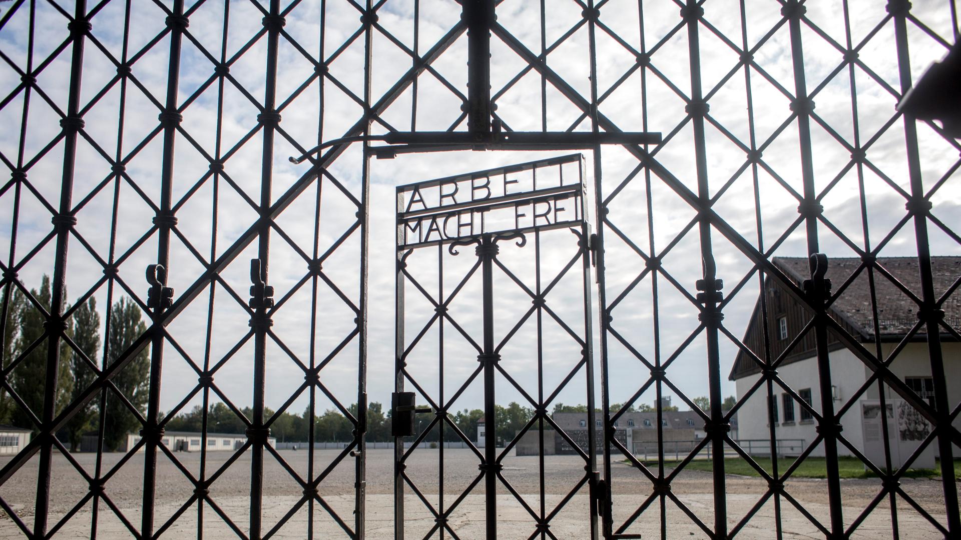 Das Foto zeigt das Eingangstor zum ehemaligen Apellhofplatz in der heutigen KZ-Gedenkstätte Dachau. Die Tür trägt die Nazi-Inschrift „Arbeit macht frei“.