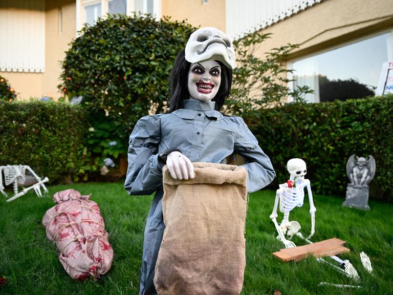 Gruselige Figuren auf einem Rasen vor einem Haus.