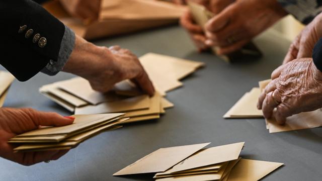 Auf einem Tisch sind beige Umschläge, die sortiert werden. Es handelt sich um Wahlumschläge bei der Europawahl am 9. Juni.