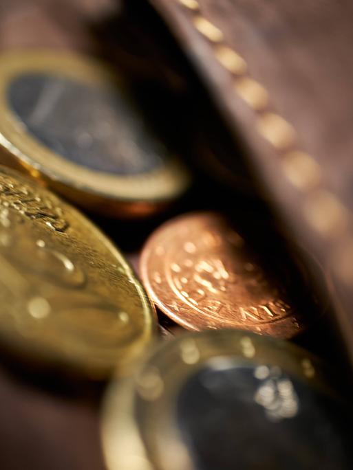 Nahaufnahme von Euromünzen, die aus einem ledernen Geldbeutel herausschauen.