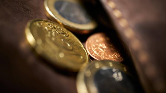 Nahaufnahme von Euromünzen, die aus einem ledernen Geldbeutel herausschauen.