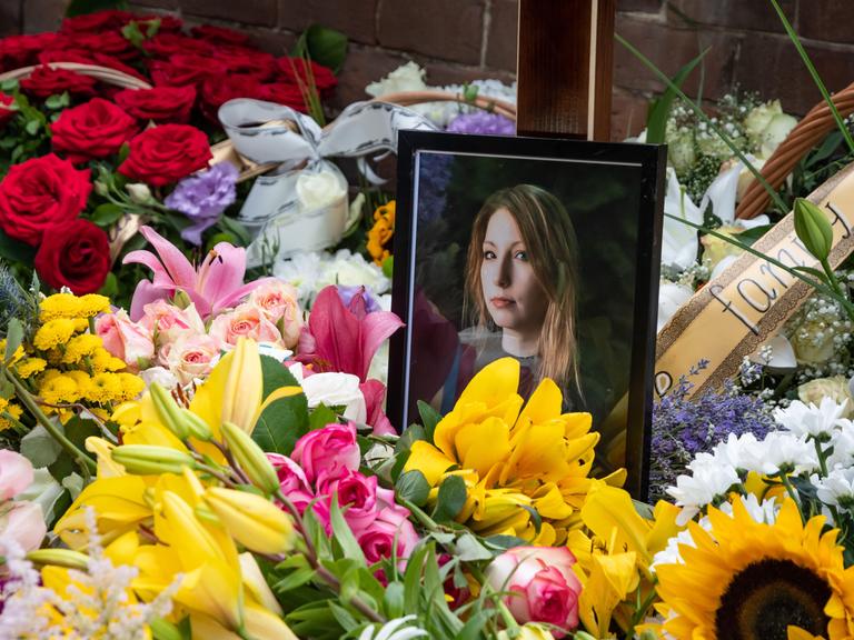 Ein von Blumen umgebendes Foto von Victoria Amelina in einer Kirche bei der Trauerfeier für die verstorbene Schriftstellerin