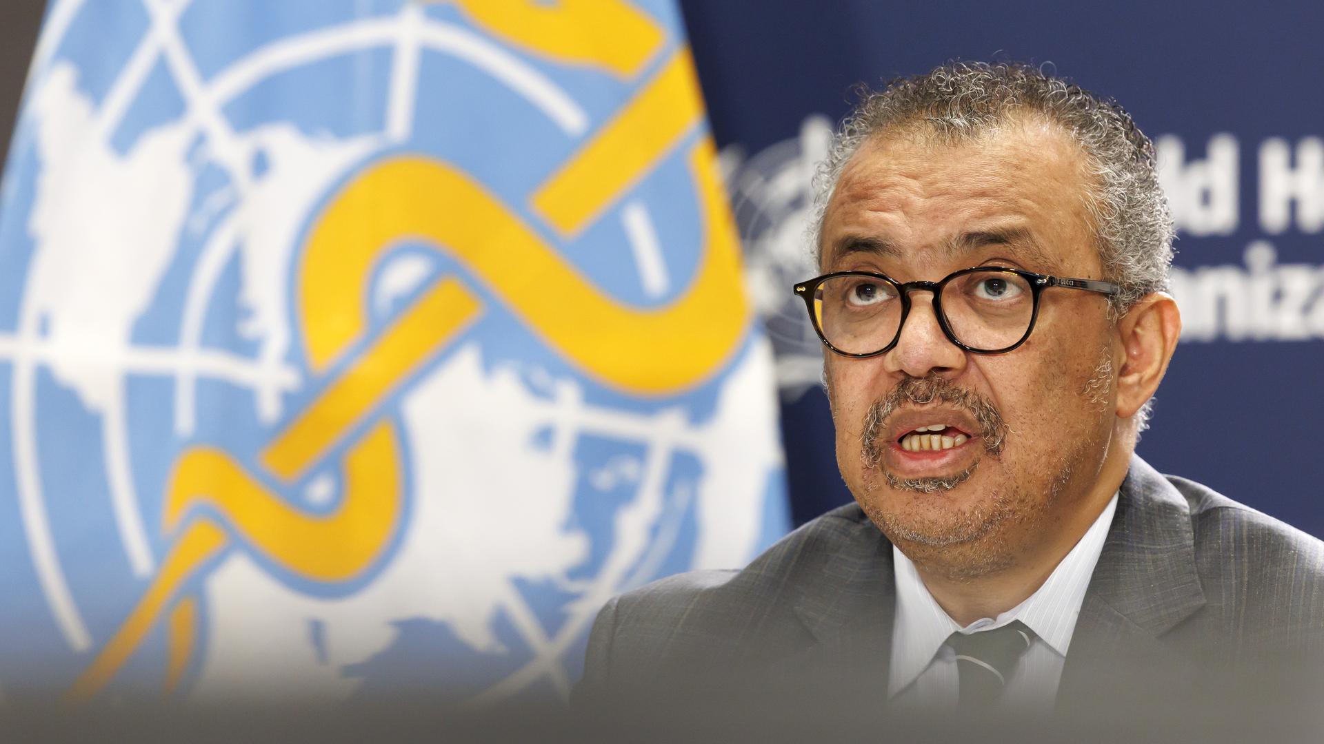 WHO-Generaldirektor Tedros spricht auf einer Pressekonferenz, er trägt eine Brille und einen Schnurrbart. Im Hintergrund ist das Logo der WHO zu sehen. Aufnahme vom 15.12.2023. 