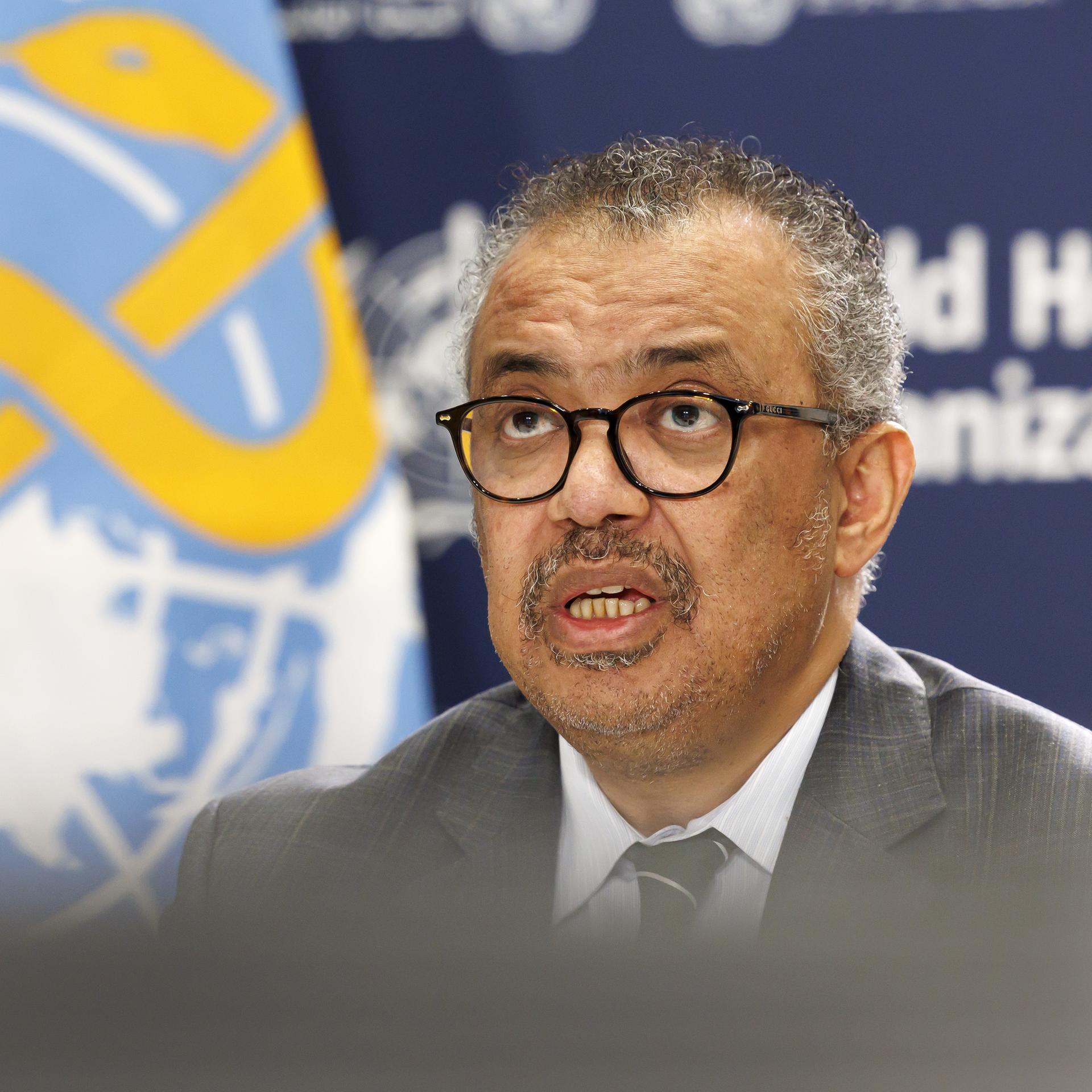 WHO-Generaldirektor Tedros spricht auf einer Pressekonferenz, er trägt eine Brille und einen Schnurrbart. Im Hintergrund ist das Logo der WHO zu sehen. Aufnahme vom 15.12.2023. 