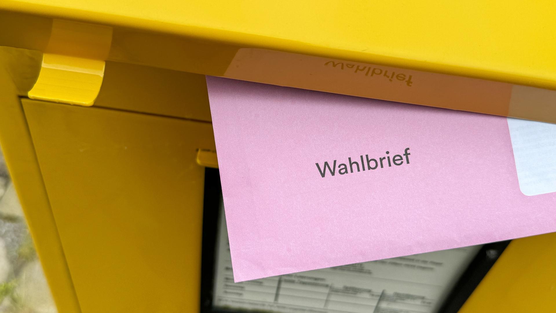 Der rote Wahlbrief für die Briefwahl zur Europawahl 2024 steckt im Briefschlitz eines Briefkastens der Deutsche Post.