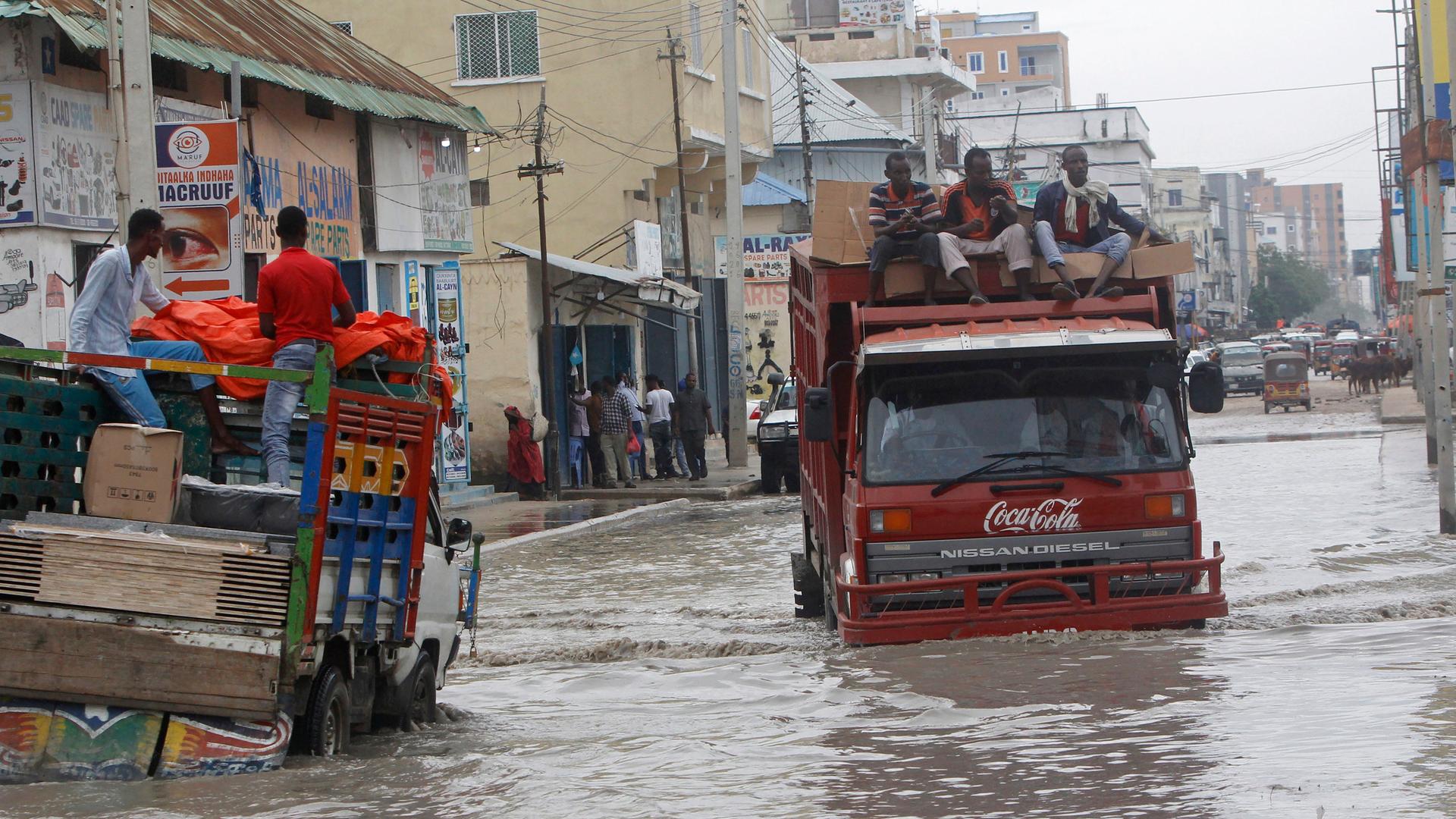 Lastwagen kämpfen sich in Mogadischu durch eine überflutete Straße.