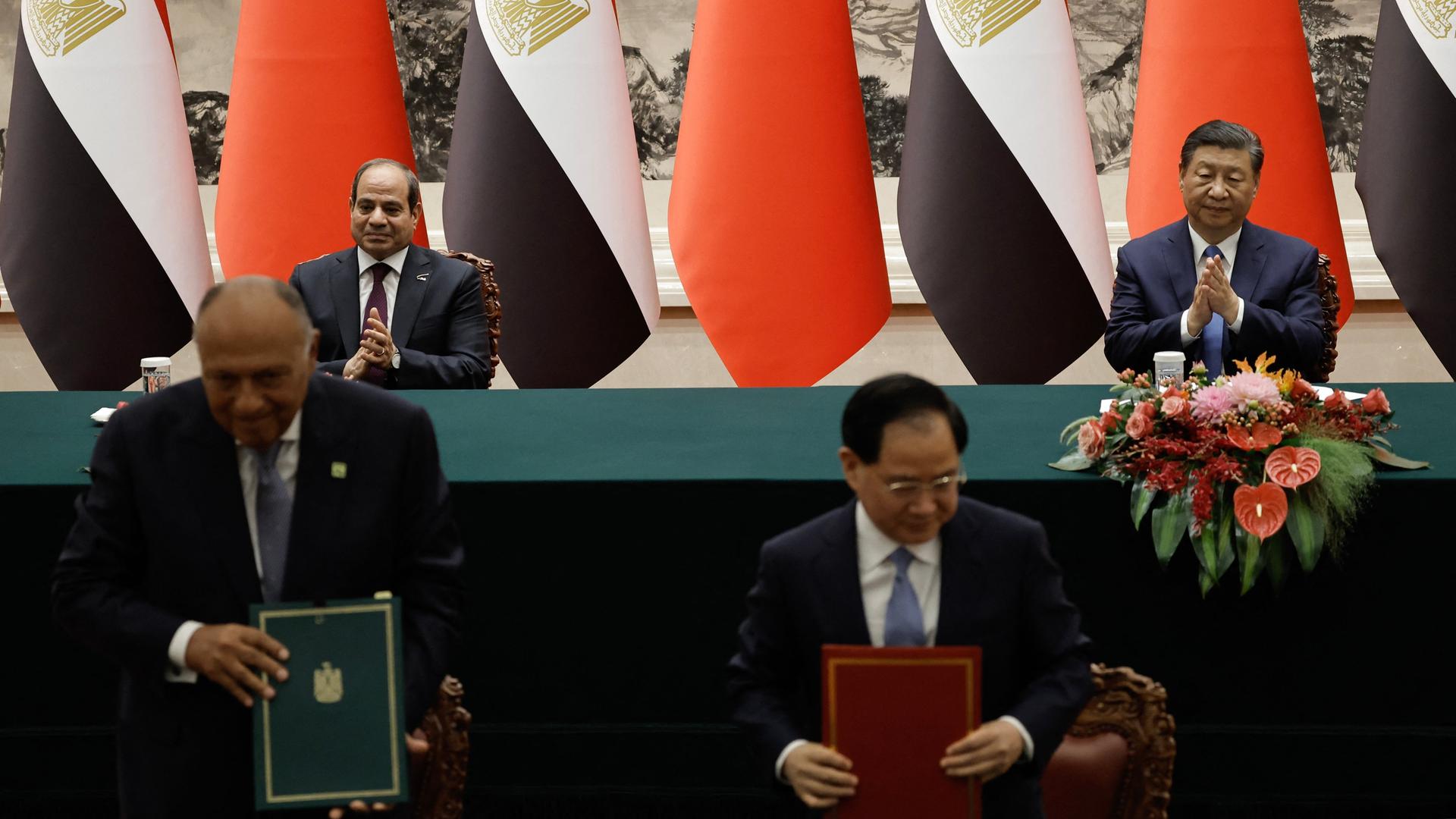 Chinas Präsident Xi Jinping und sein ägyptischer Amtskollege al-Sisi unterzeichnen in Peking ein bilaterales Abkommen zur wirtschaftlichen Zusammenarbeit. Im Vordergrund zeigen zwei Männer die Dokumente vor.