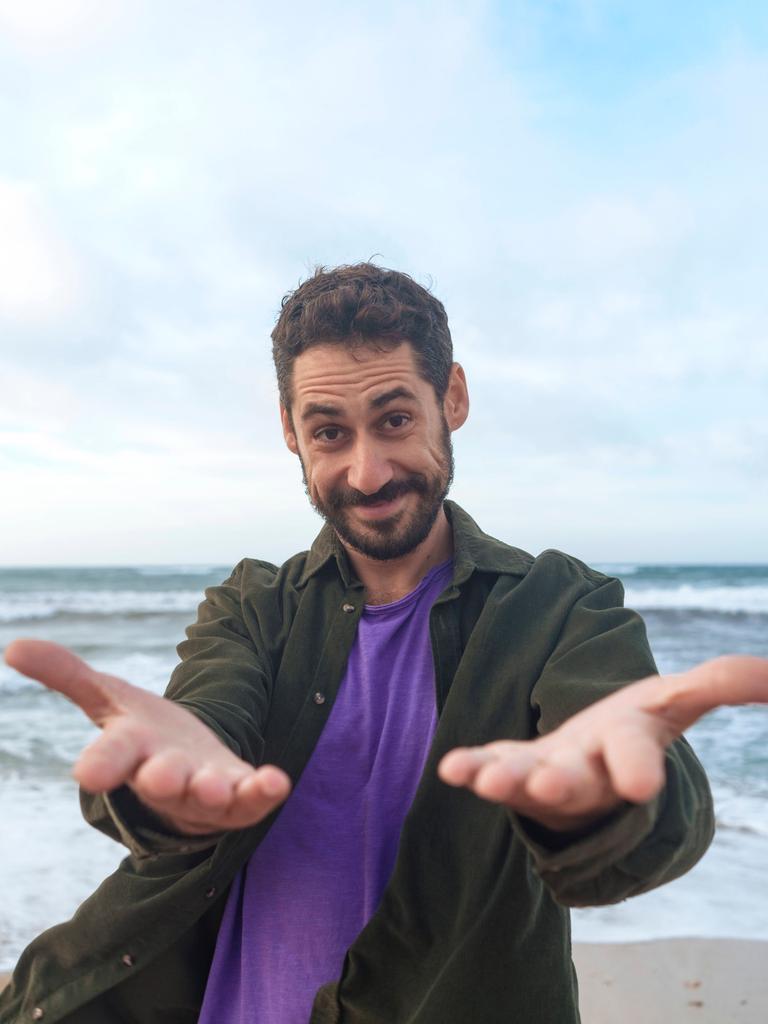 Ein Mann steht am Strand und führt lächelnd ein Selbstgespräch.
