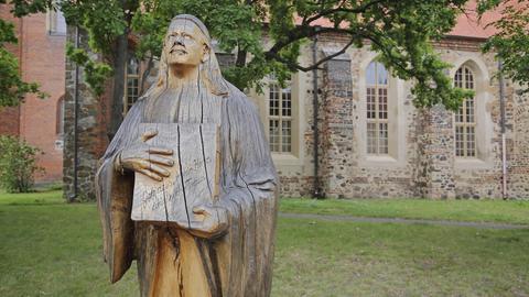 Denkmal von 1911 an Kirchenlieddichter Paul Gerhardt und Buch mit Liederbuch und Inschrift zum Lied : Geh aus mein Herz und suche Freud, vor einer Kirche in Gräfenhainichen, Sachsen-Anhalt