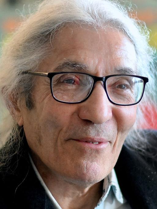 Das Bild zeigt den algerischen Schriftsteller Boualem Sansal. Er hat längere weiße Haare und trägt eine schwarze Brille.