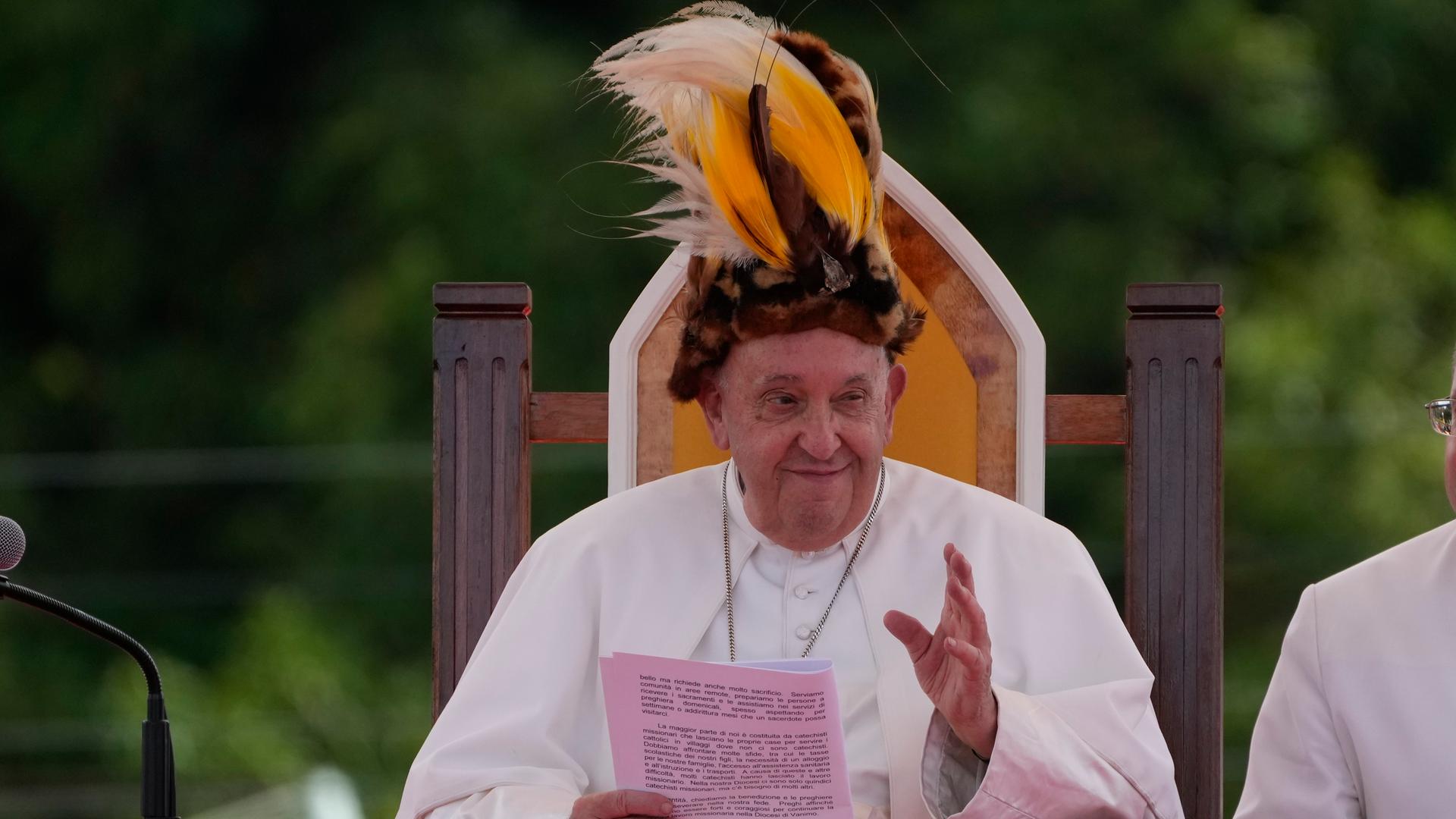 Papst Franziskus trägt einen traditionellen Hut bei einem Treffens mit Gläubigen in Vanimo, Papua-Neuguinea. Er lächelt und winkt.