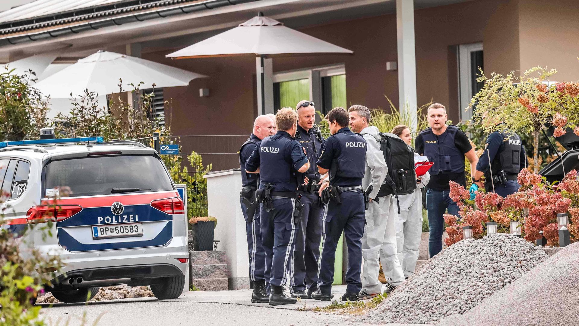 Österreichische Polizisten stehen vor einem Wohnhaus.