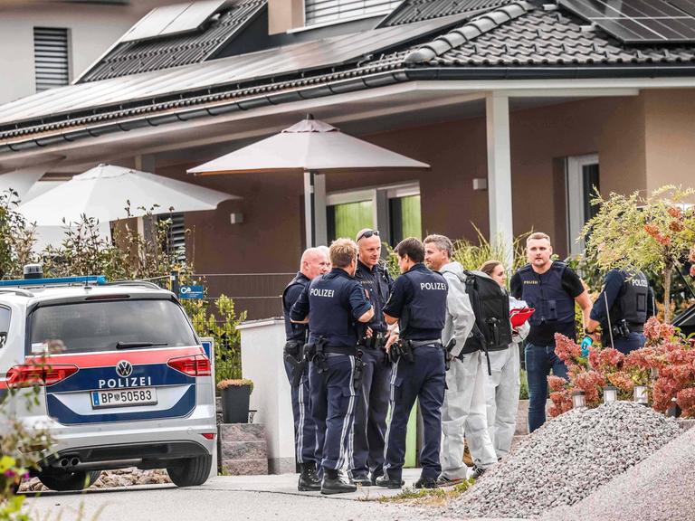 Österreichische Polizisten stehen vor einem Wohnhaus.