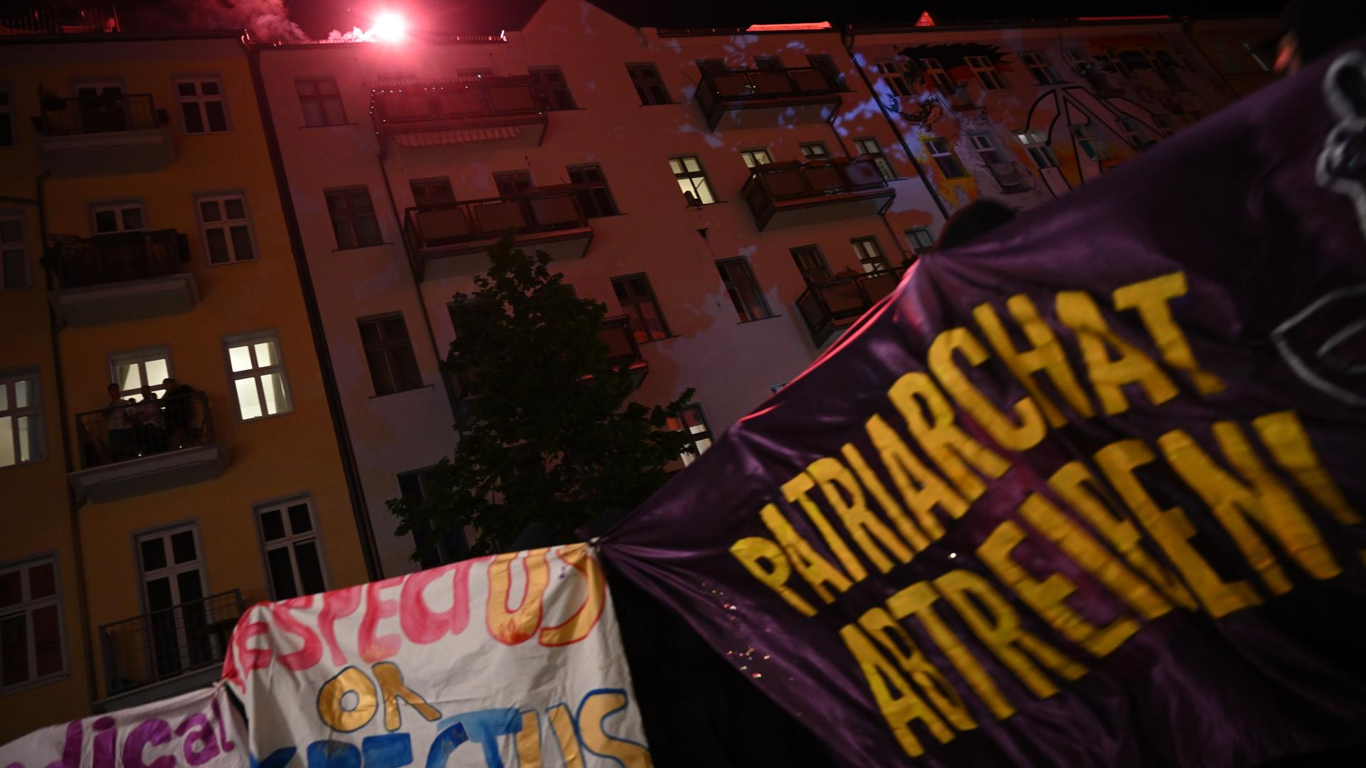 Demonstranten hissen Fahnen. Auf einer steht: "Patriarchat Abtreten!"