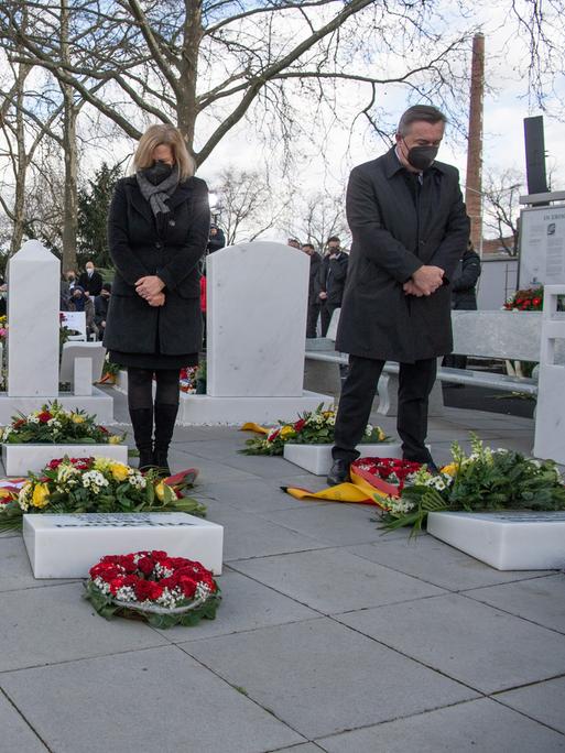 Volker Bouffier, Nancy Faeser und Claus Kaminsky stehen mit gesenkten Köpfen vor dem Grab. Im Hintergrund ist eine größere Trauergemeinde zu sehen.