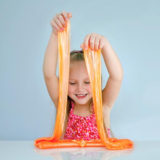 Ein Mädchen spielt mit einer großen Portion orangefarbenem Schleim