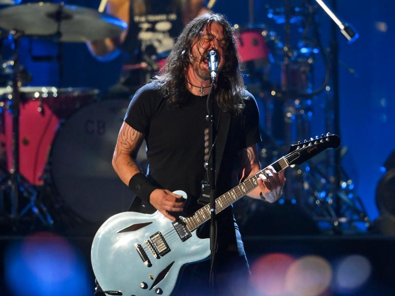 Dave Grohl spielt bei einem Konzert der Foo Fighters verschwitzt und mit wilden langen Haaren Gitarre. Foto: picture alliance