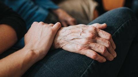 Eine jüngere Hand hält eine ältere Hand.
