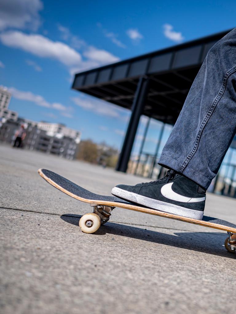 Ein Jugendlicher steht mit einem Bein auf einem Skateboard. 