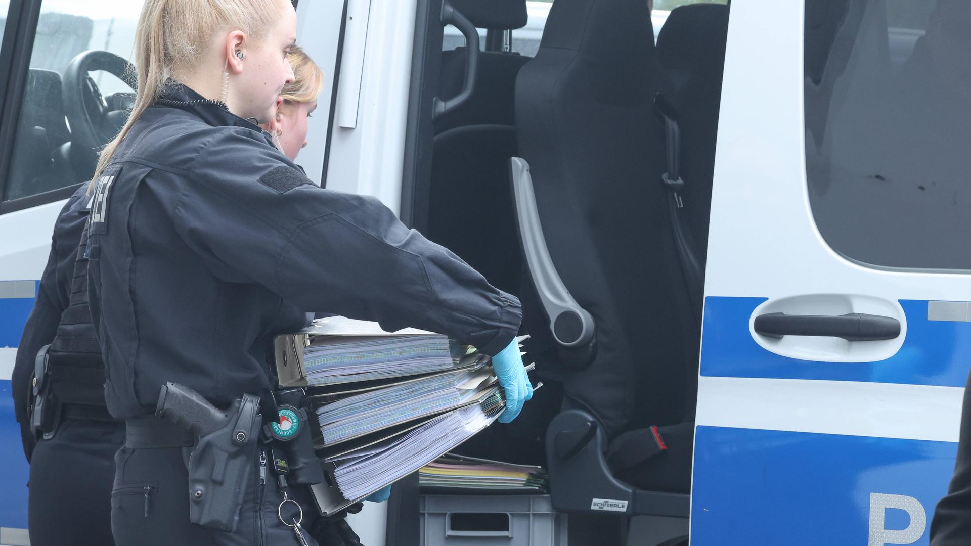 Hannover: Bei der Razzia in der Landesstelle der AfD haben die Beamten Beweismaterial gesichert. Zwei Polizistinnen tragen Aktenordner in ein Polizeifahrzeug.