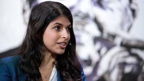 Eine Frau mit schwarzen Haaren, Daniela Sepehri, Aktivistin aus dem Iran, schaut während des Redens nach rechts. Sie hat ein Mikrofon an. 