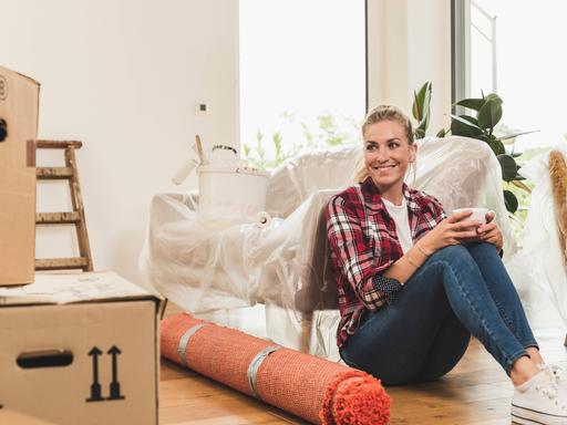Eine Frau sitzt neben Umzugskartons. Eine Frau sitzt neben Umzugskartons.