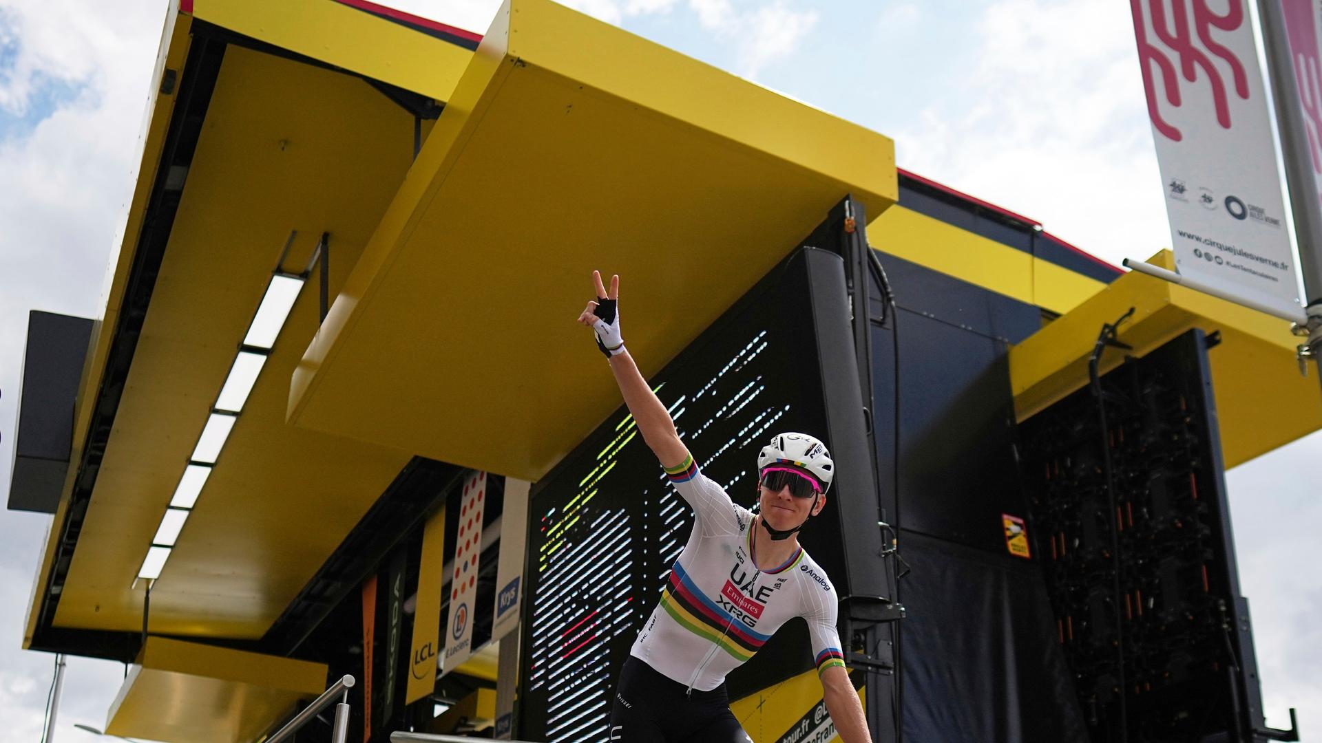 Der slowenische Radrennfahrer Tadej Pogacar zeigt mit der rechten Hand das Victory-Zeichen. Der slowenische Radrennfahrer Tadej Pogacar zeigt mit der rechten Hand das Victory-Zeichen.
