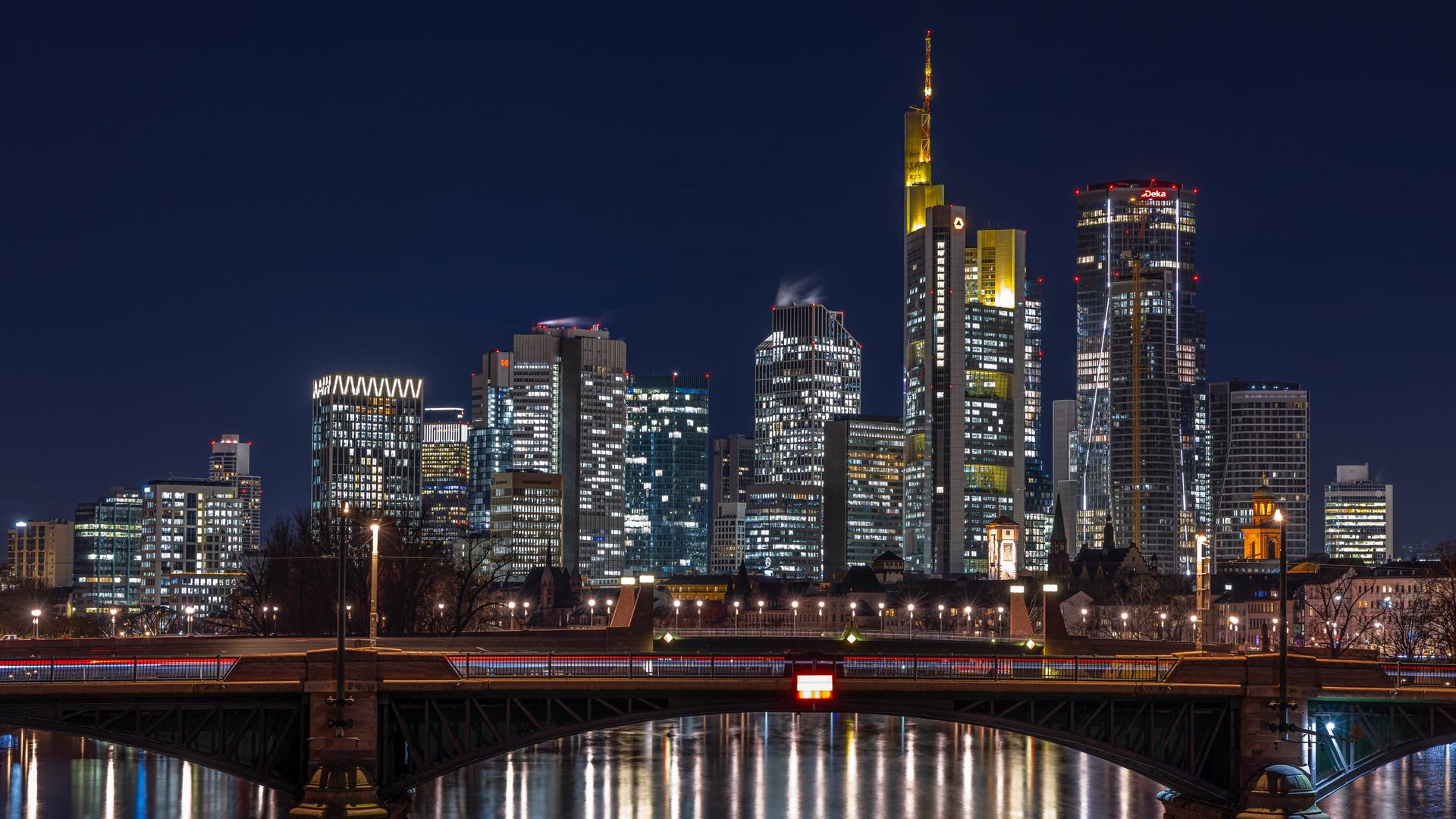 Die Lichter in den Büros der Frankfurter Bankenskyline leuchten am Abend und spiegeln sich im Wasser