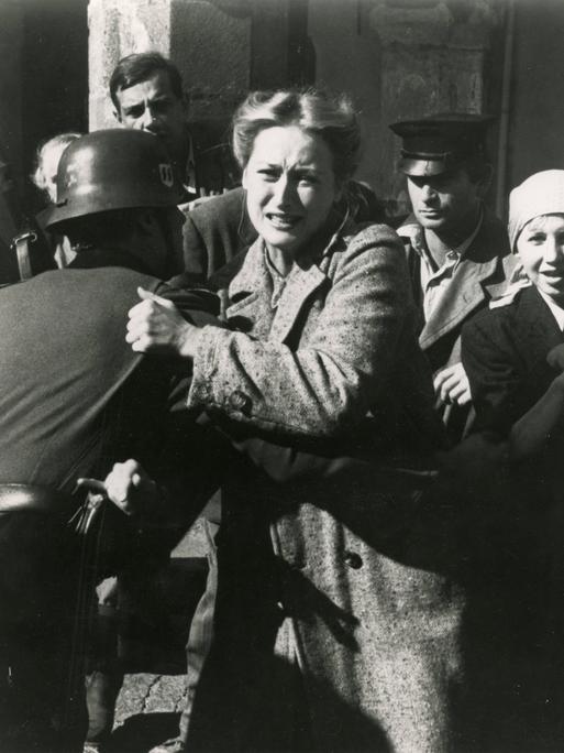 Standfoto aus der Serie "Holocaust", auf dem Meryl Streep von einem Soldaten mit Stahlhelm festgehalten, während sie versucht, sich mit schmerz verzerrtem Gesicht loszureißen. Standfoto aus der Serie "Holocaust", auf dem Meryl Streep von einem Soldaten mit Stahlhelm festgehalten, während sie versucht, sich mit schmerz verzerrtem Gesicht loszureißen.