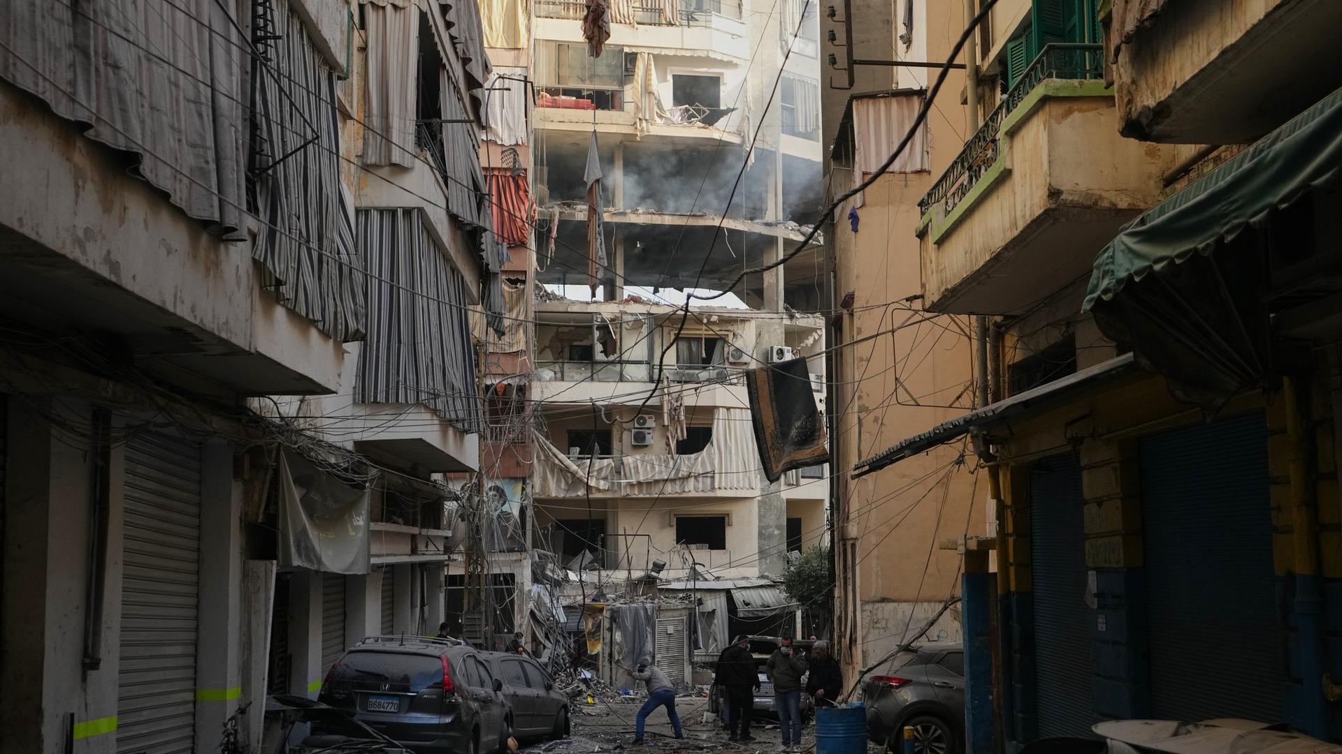 Leute gehen an einem zerstörten Gebäude vorbei.