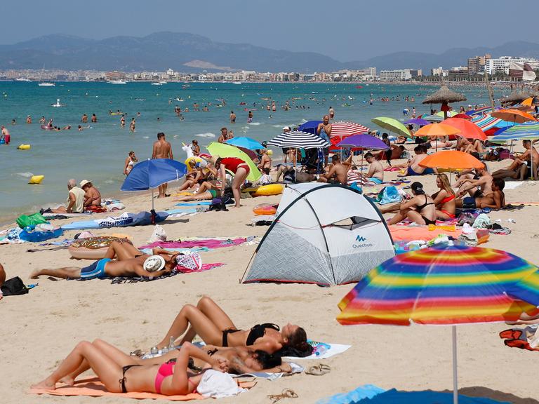Touristen sonnen sich am Strand von El Arenal auf der Balearen-Insel Mallorca. 