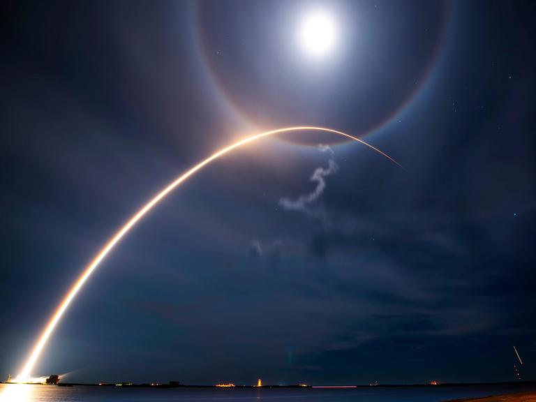 Lichtbogen einer abhebenden SpaceX-Rakete, die vom Kennedy Space Center Starlink-Satelliten in die Umlaufbahn bringt Lichtbogen einer abhebenden SpaceX-Rakete, die vom Kennedy Space Center Starlink-Satelliten in die Umlaufbahn bringt