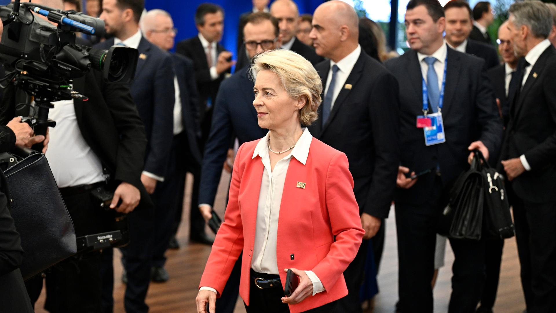 EU-Kommissionspräsidentin Ursula von der Leyen steht bei einem Treffen von Staatschefs inmitten schwarz gekleideter Männer.