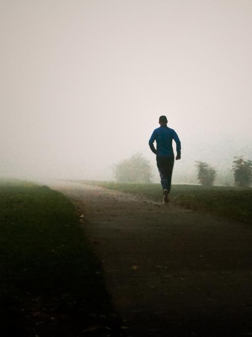 Ein Mann joggt im Nebel.