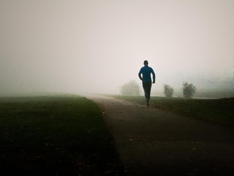 Ein Mann joggt im Nebel.