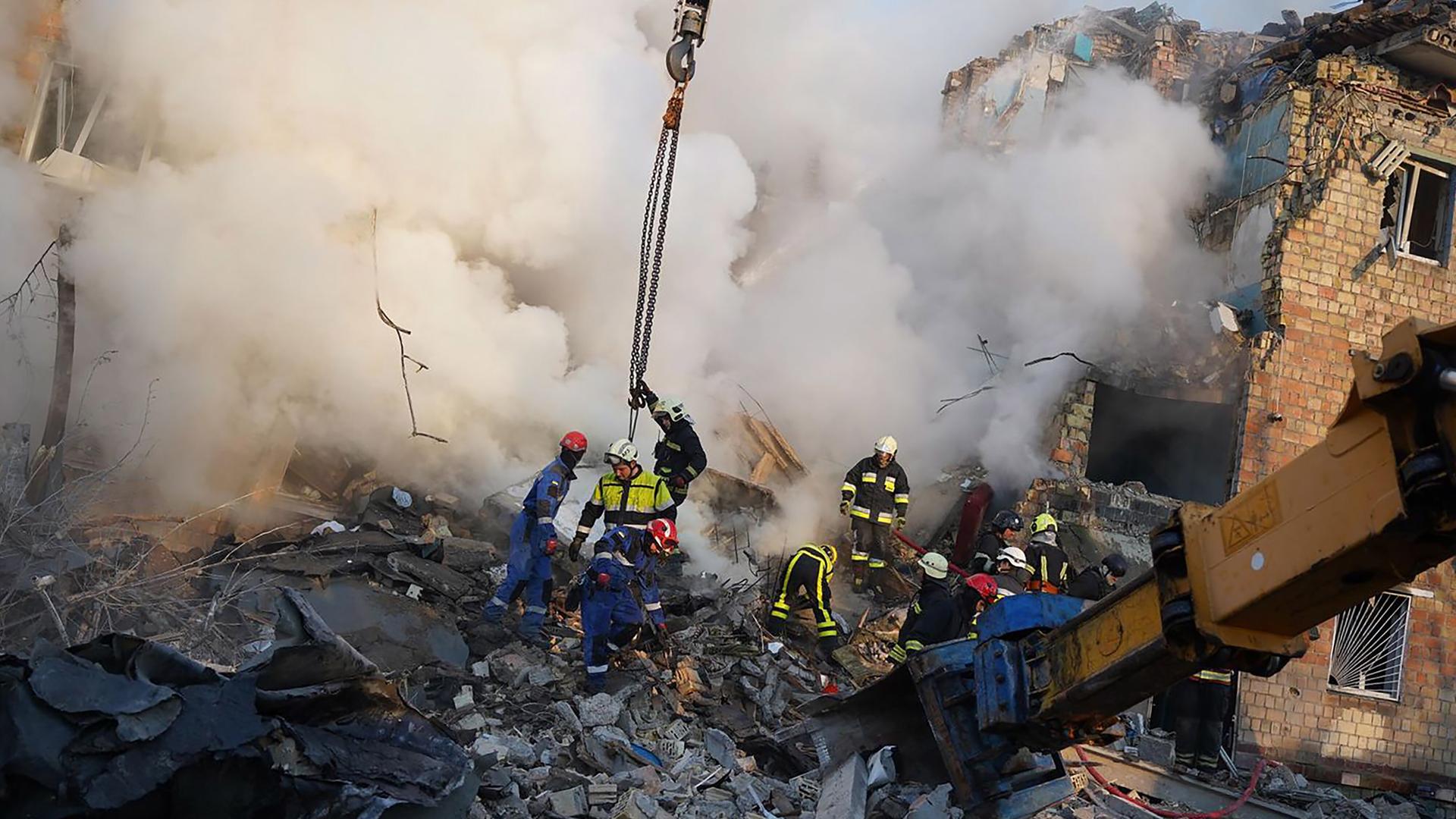 Feuerwehrleute versuchen, aus den Trümmern eines Hauses durch eine große Staubwolke Menschen zu finden. Feuerwehrleute versuchen, aus den Trümmern eines Hauses durch eine große Staubwolke Menschen zu finden.