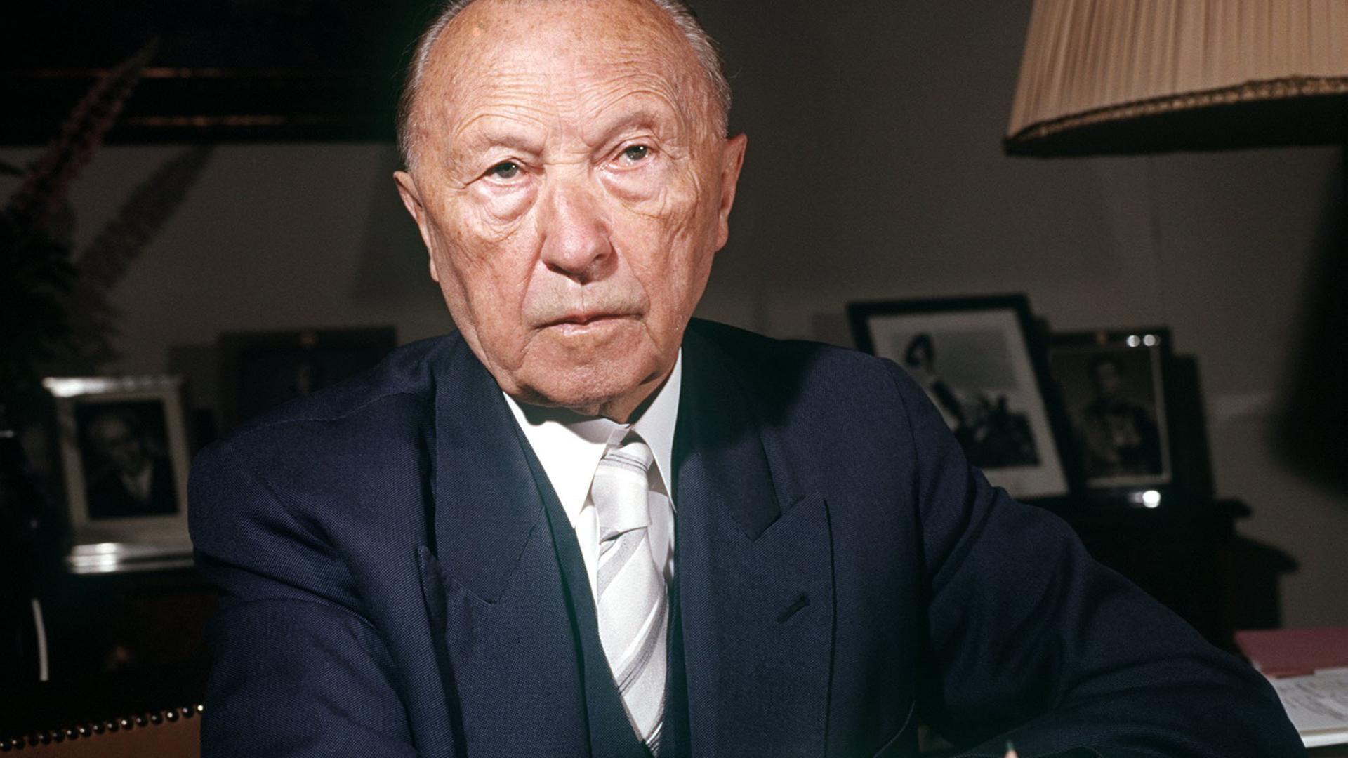 Konrad Adenauer sitzt an einem Schreibtisch.