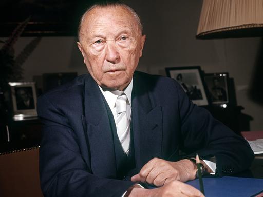 Konrad Adenauer sitzt an einem Schreibtisch.