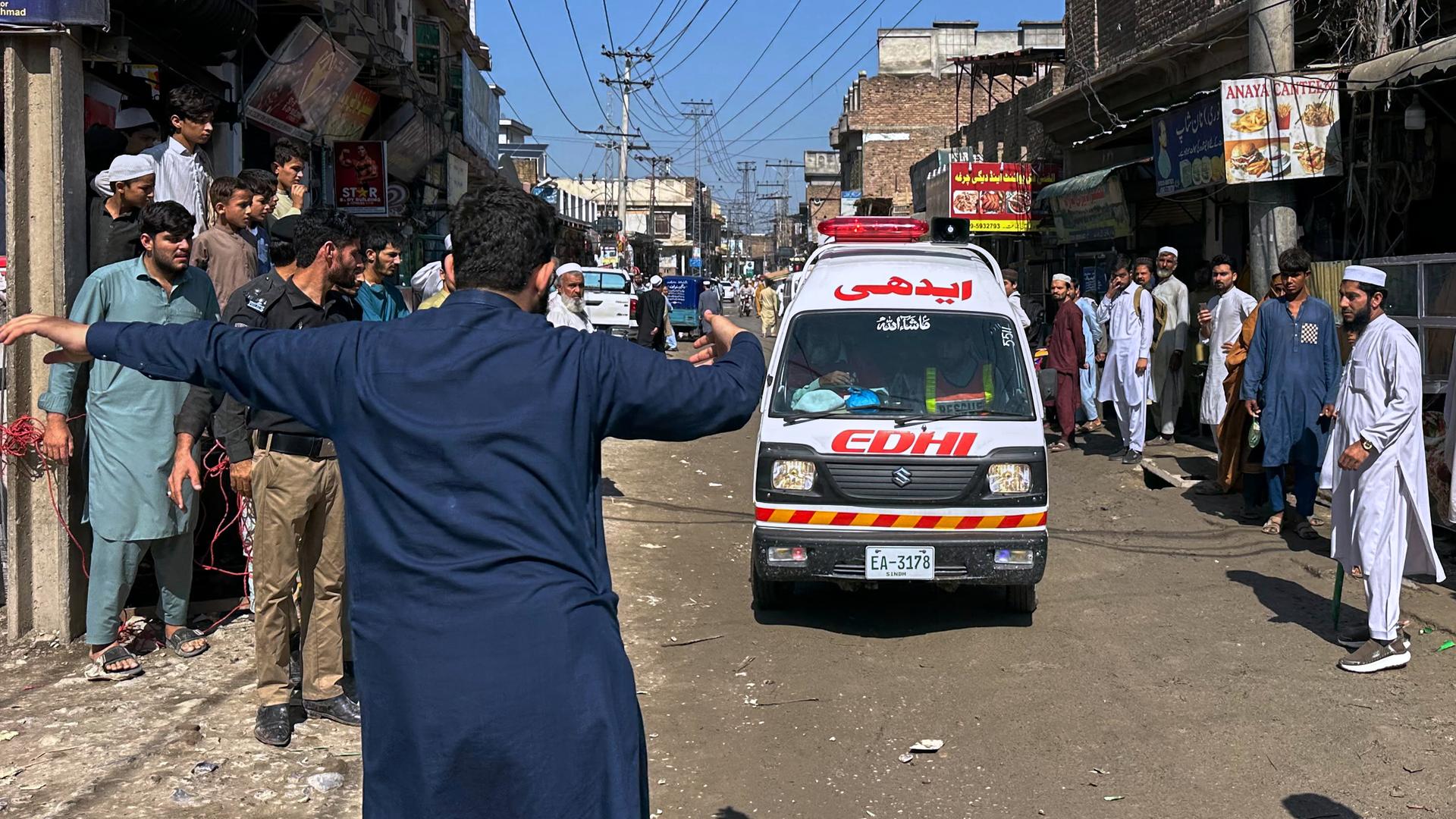 Peshawar: Ein Freiwilliger macht den Weg frei für einen Krankenwagen, der verletzte Schulkinder nach einem Dacheinsturz an einer Privatschule in Peshawar transportiert.