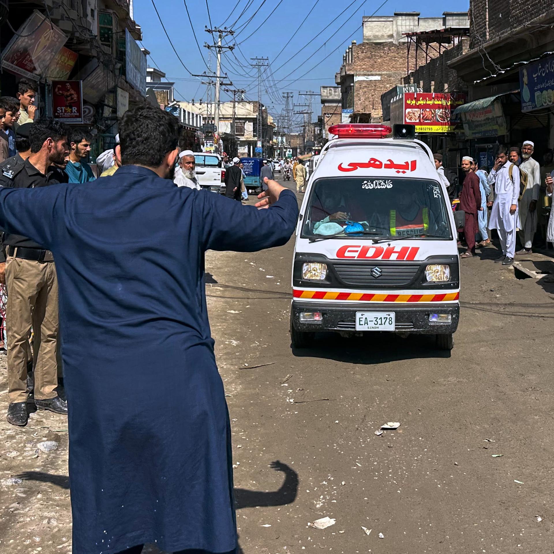 Peshawar: Ein Freiwilliger macht den Weg frei für einen Krankenwagen, der verletzte Schulkinder nach einem Dacheinsturz an einer Privatschule in Peshawar transportiert.