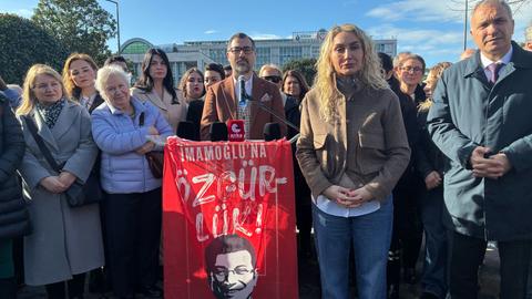 Dilek Imamoglu, Frau des inhaftierten und abgesetzten Bürgermeisters von Istanbul, nimmt an einer Kundgebung teil, auf der Freiheit für ihren Mann gefordert wird. Neben ihr stehen Männer und Frauen. Im Hintergrund ist ein Gebäude. Der Himmel ist blau.