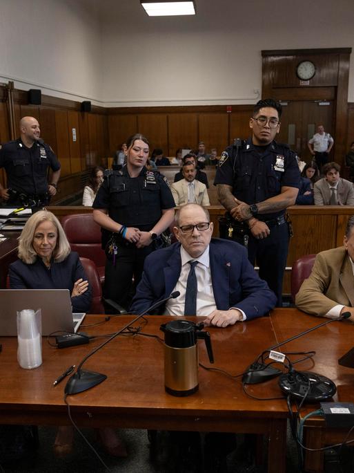 Harvey Weinstein sitzt in einem Gerichtssaal zwischen seinen Anwälten
