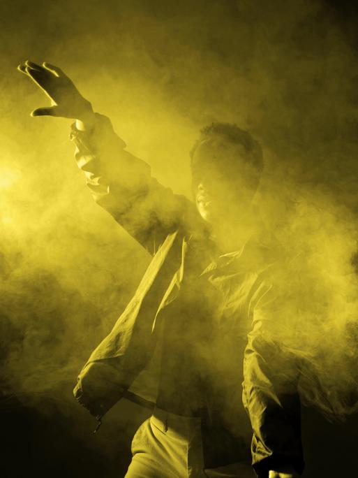 Ein junger Mann tanzt in einem verrauchten Club mit leuchtendem Licht